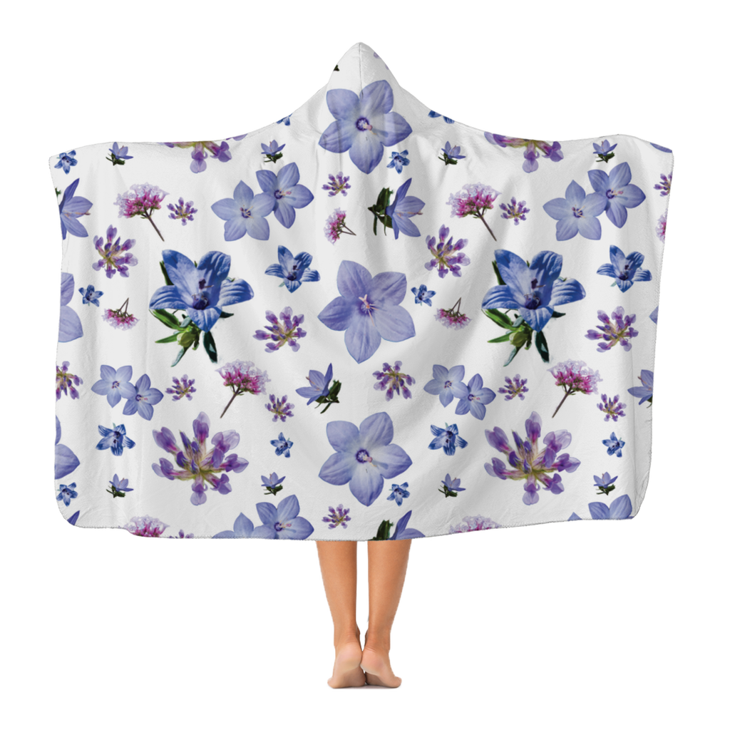 A woman wearing a gorgeous hooded white blanket with a large print repeating floral pattern.