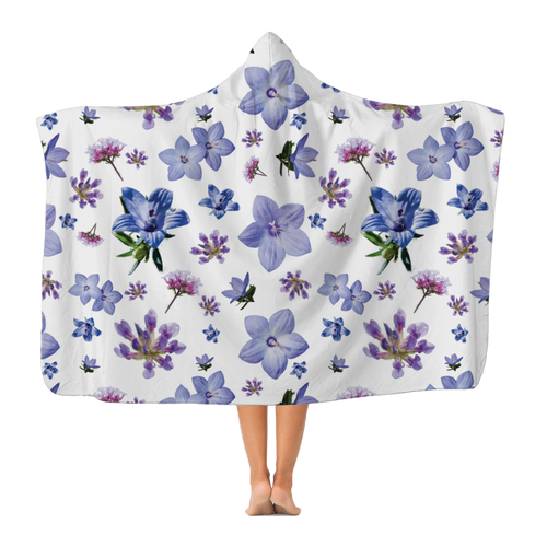 A woman wearing a gorgeous hooded white blanket with a large print repeating floral pattern.