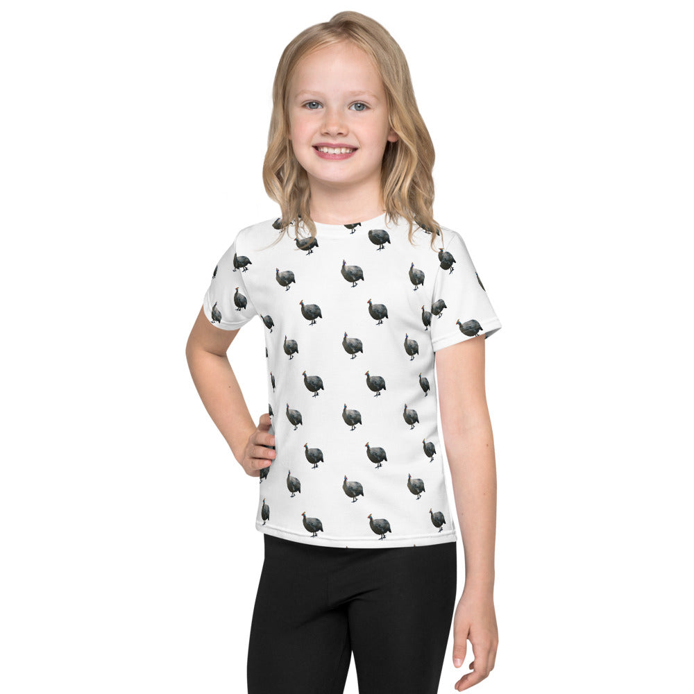 A child wearing a white t-shirt with a guinea fowl pattern.